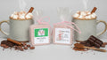 Two soap bars in pink packaging with labels with 2 cups of cocoa