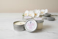Four small jars with lids on a white table flowers in background