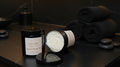 Two black containers with white lids on a wooden surface