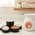 Black tins labeled 'Wax Melt Buttons' with pink labels on a light gray background