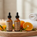 Two brown glass bottles of face serum with black droppers on a white background