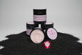 Jars of tallow body butter with visible labels on a black textured surface.